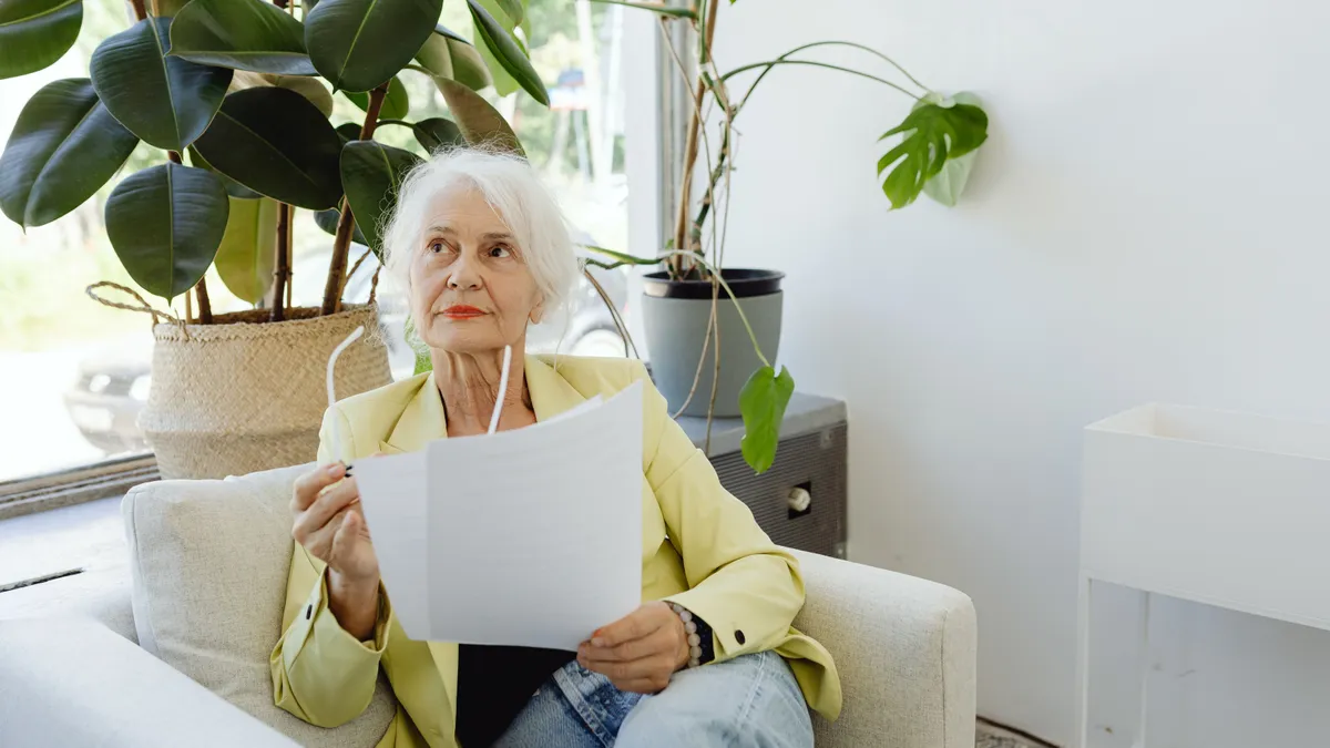 Pensionară care ține un document în mână