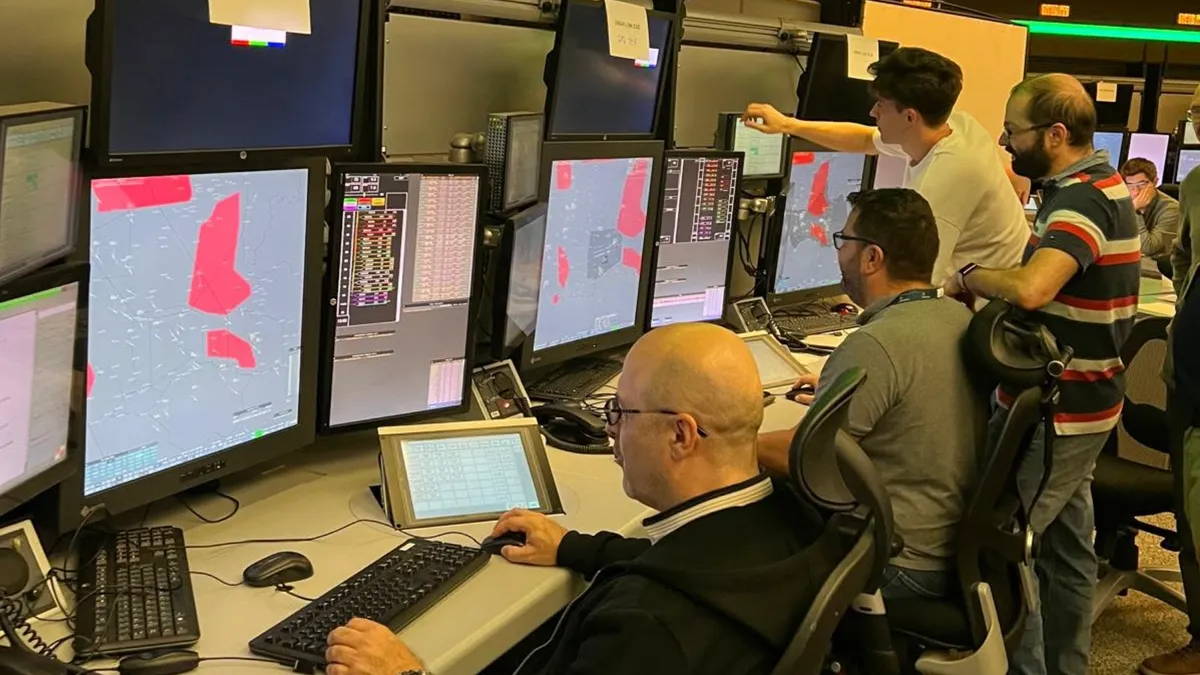 Controlori de zbor în fața calculatoarelor cu hărți aviatice