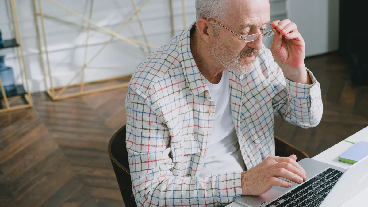 Pensionar care caută informații pe un laptop