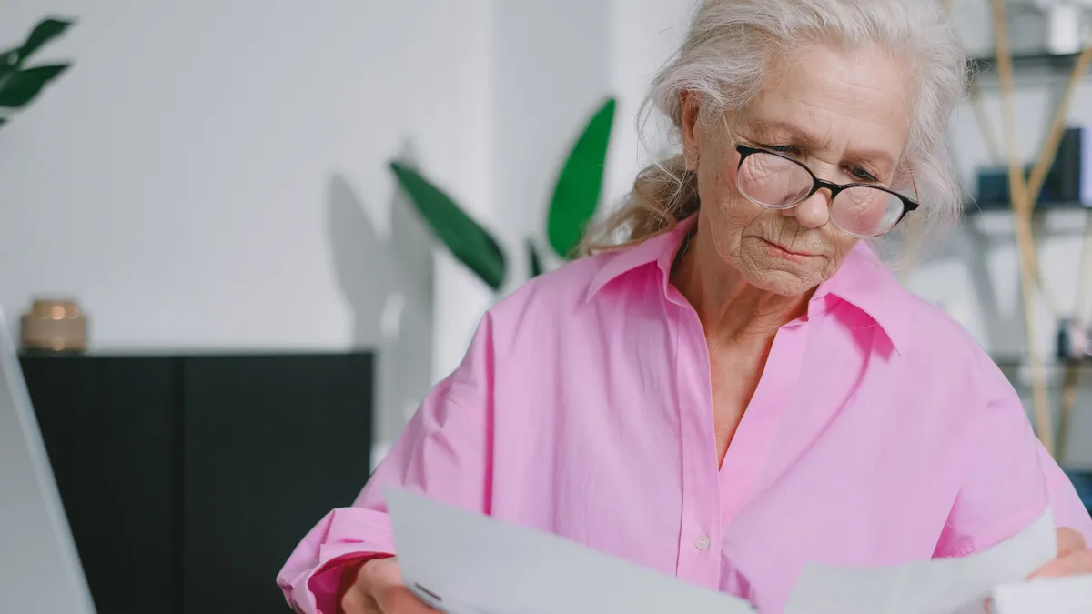 Pensionară care verifică posibile probleme în acte