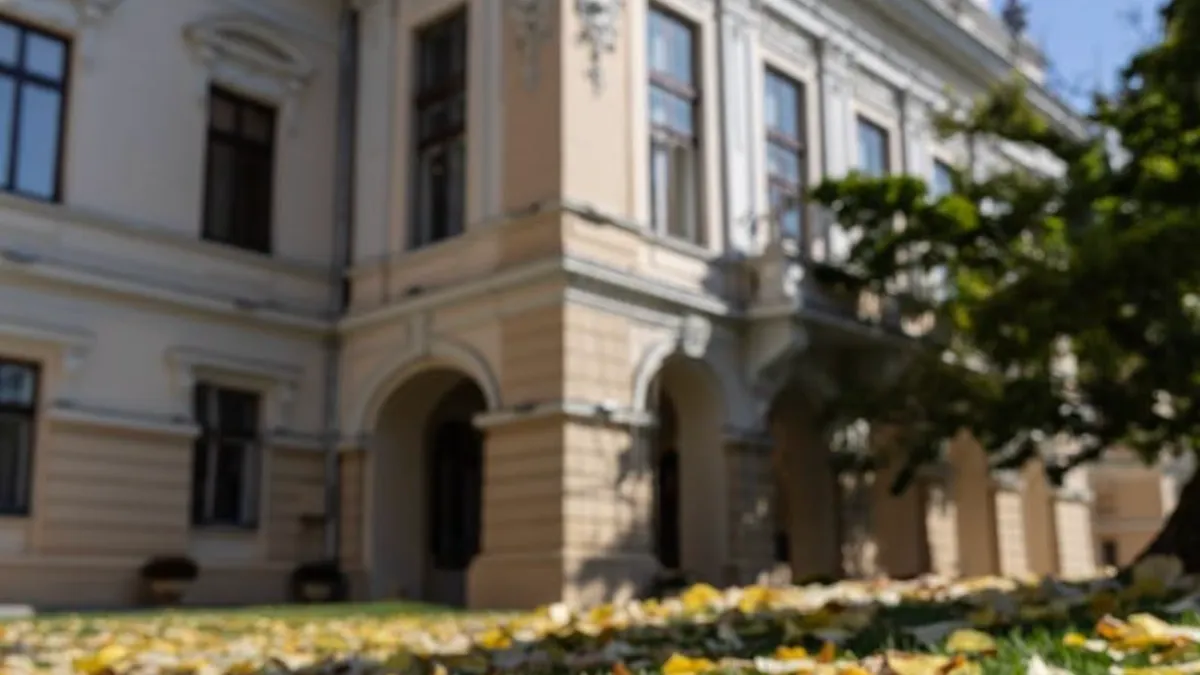 fațada primăriei municipiului iași în cadru îndepărtat, frunze galbene pe iarbă în prim plan