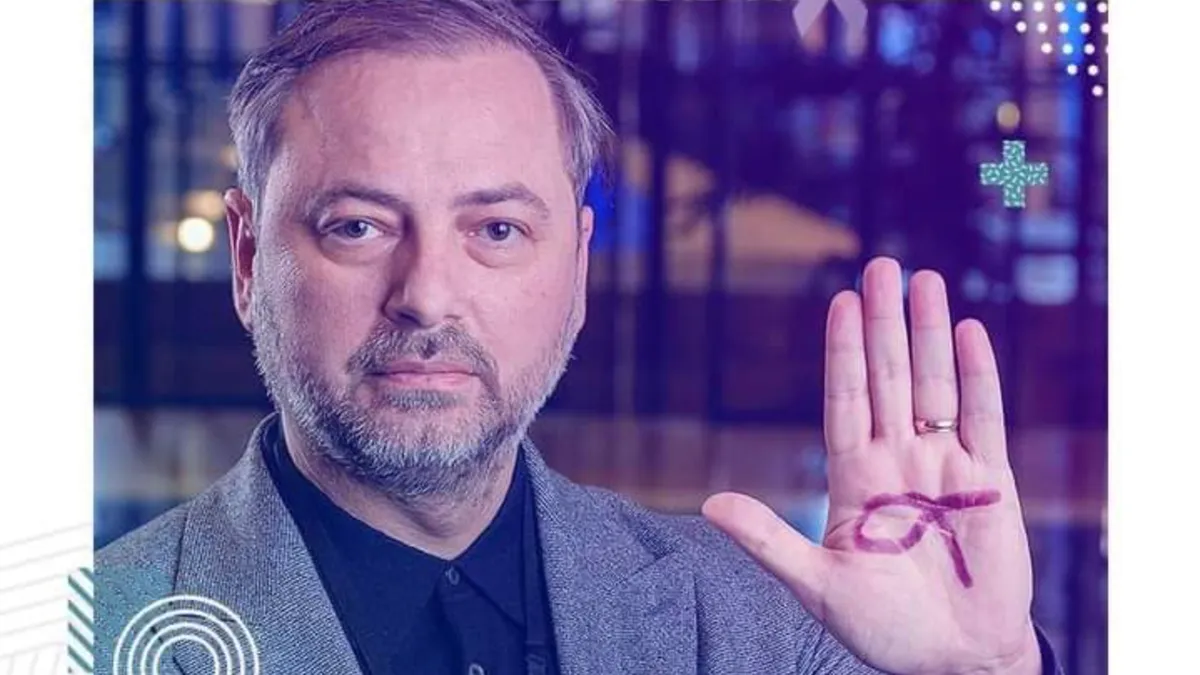 Dan Motreanu cu palma stângă deschisă pe care are desenat simbolul luptei anti-cancer