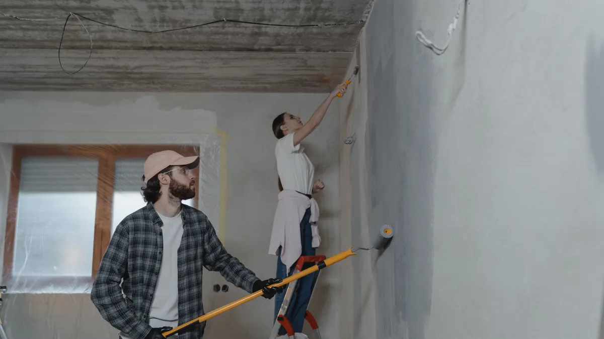 Doi oameni renovează interiorul unui apartament.