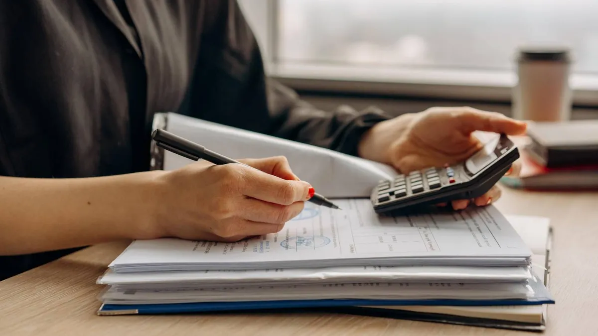 o femeie folosește un calculator de buzunar pe un dosar deschis