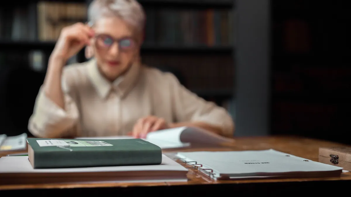 Persoana care examinează documente, cu dosarele în prim-plan