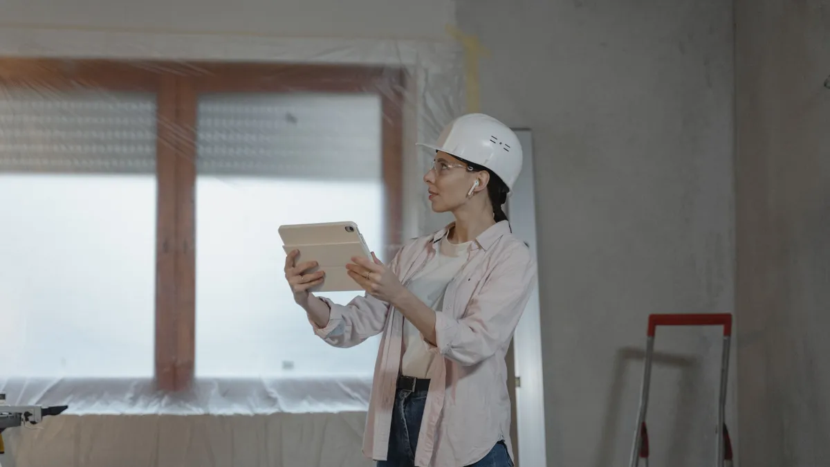 Femeie cu cască de protecție verifică un apartamen aflat în renovare.