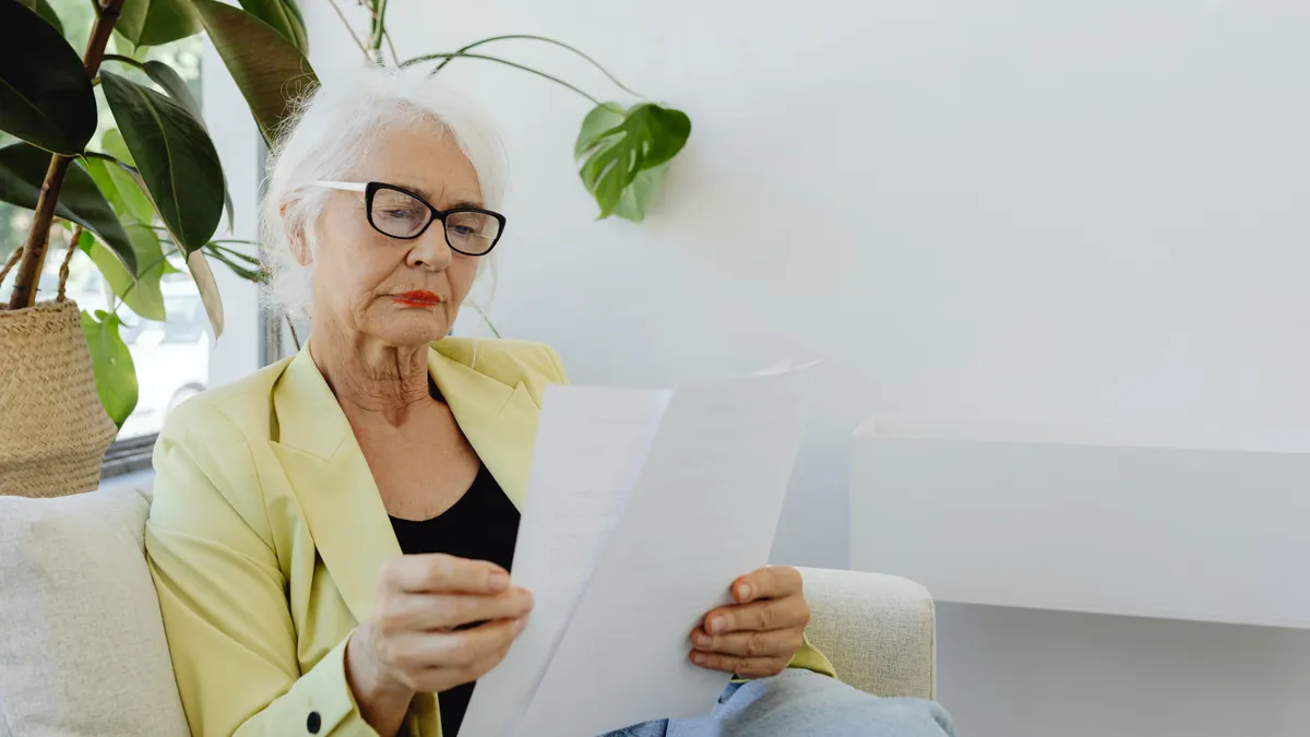 Pensionară care consultă documente.