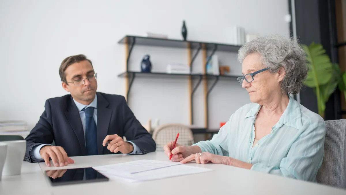 Pensionară care completează documente în prezența unui funcționar.