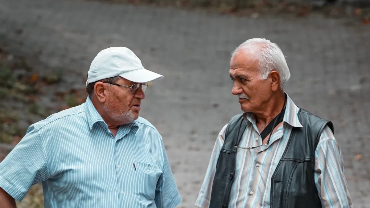 Doi bătrâni discută la o plimbare în oraș