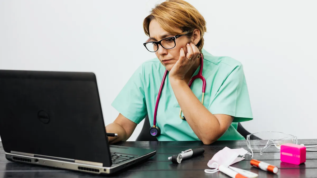 Medic în fața unui laptop