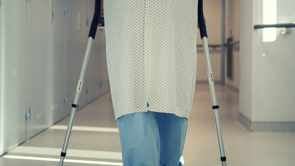 Pensionar mergând cu cârje pe holul unui spital