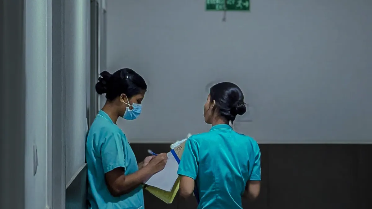 Două asistente medicale discută pe holul unui spital
