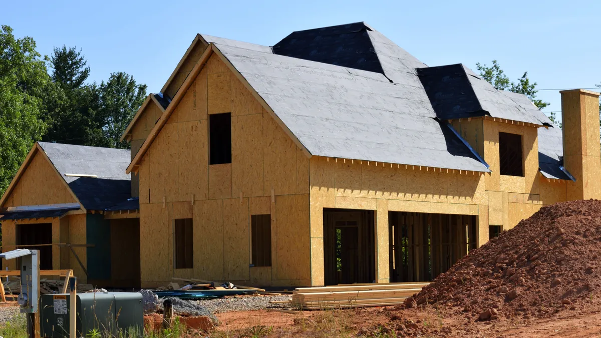 Casă aflată în construcție, cu structura și acoperișul parțial realizate.